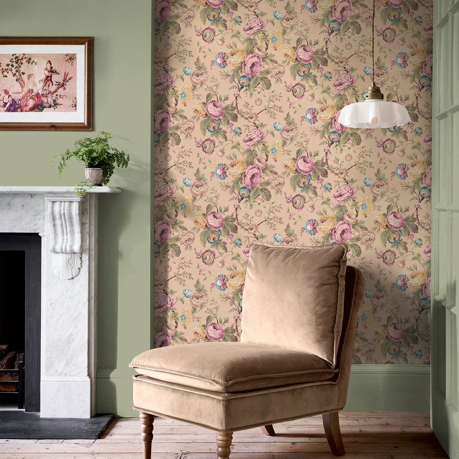 Uffington Roses in Plaster Pink by Laura Ashley, a soft rose trail in a green painted room with a marble fireplace and a velvet chair