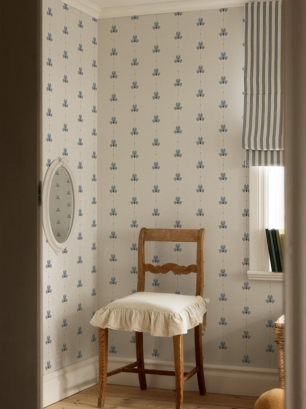 Sweet Pea Dove Blue wallpaper by Gotain for Borastapeter, a fine blue sweet pea sprig in a pale room with a slipcovered chair