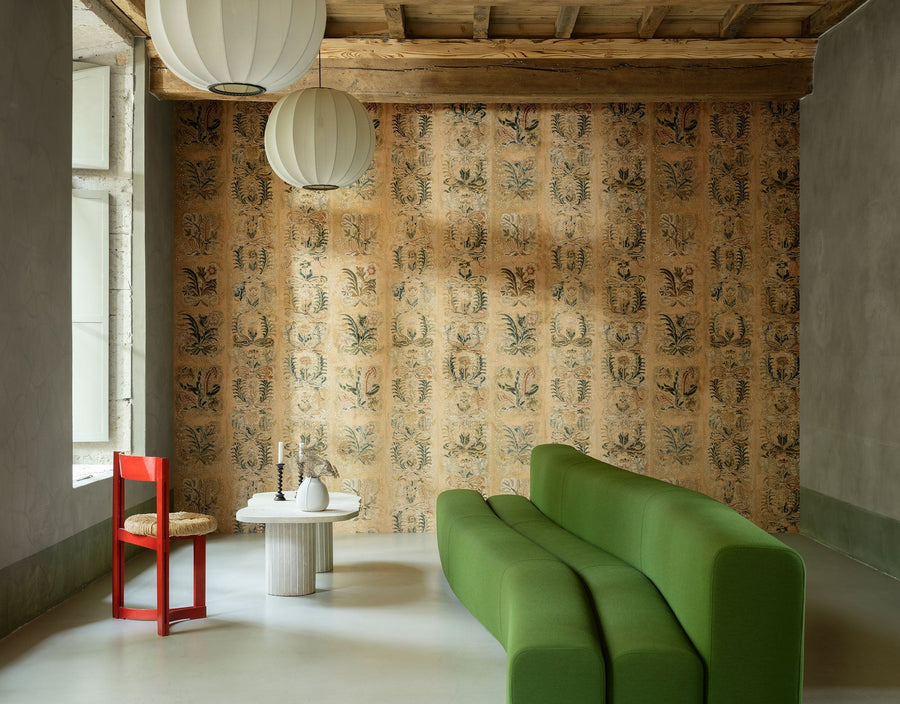 Ornement Ochre wallpaper by Arte, a soft faded gold damask in a room with a green sofa and a low table