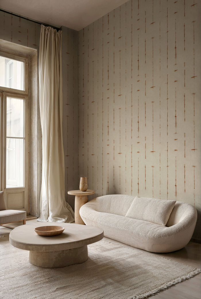 Miura in Natural from Shibori by Coordonne, a softly dyed natural wallcovering in a serene room with a curved cream sofa and a low wooden table
