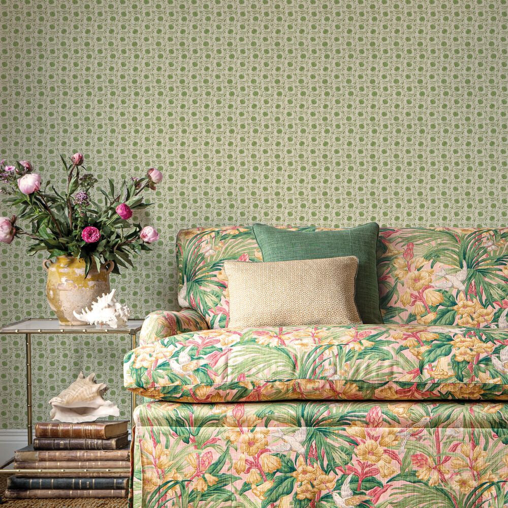 Seed Pod House Small Prints Green wallpaper by GP and J Baker, a green seed pod that reads as a polka dot, behind a floral sofa and a jug of roses