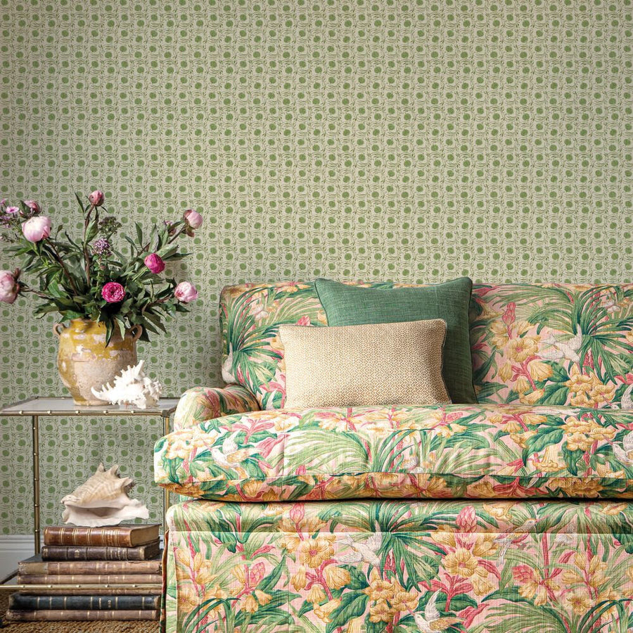 Seed Pod House Small Prints Green wallpaper by GP and J Baker, a green seed pod that reads as a polka dot, behind a floral sofa and a jug of roses