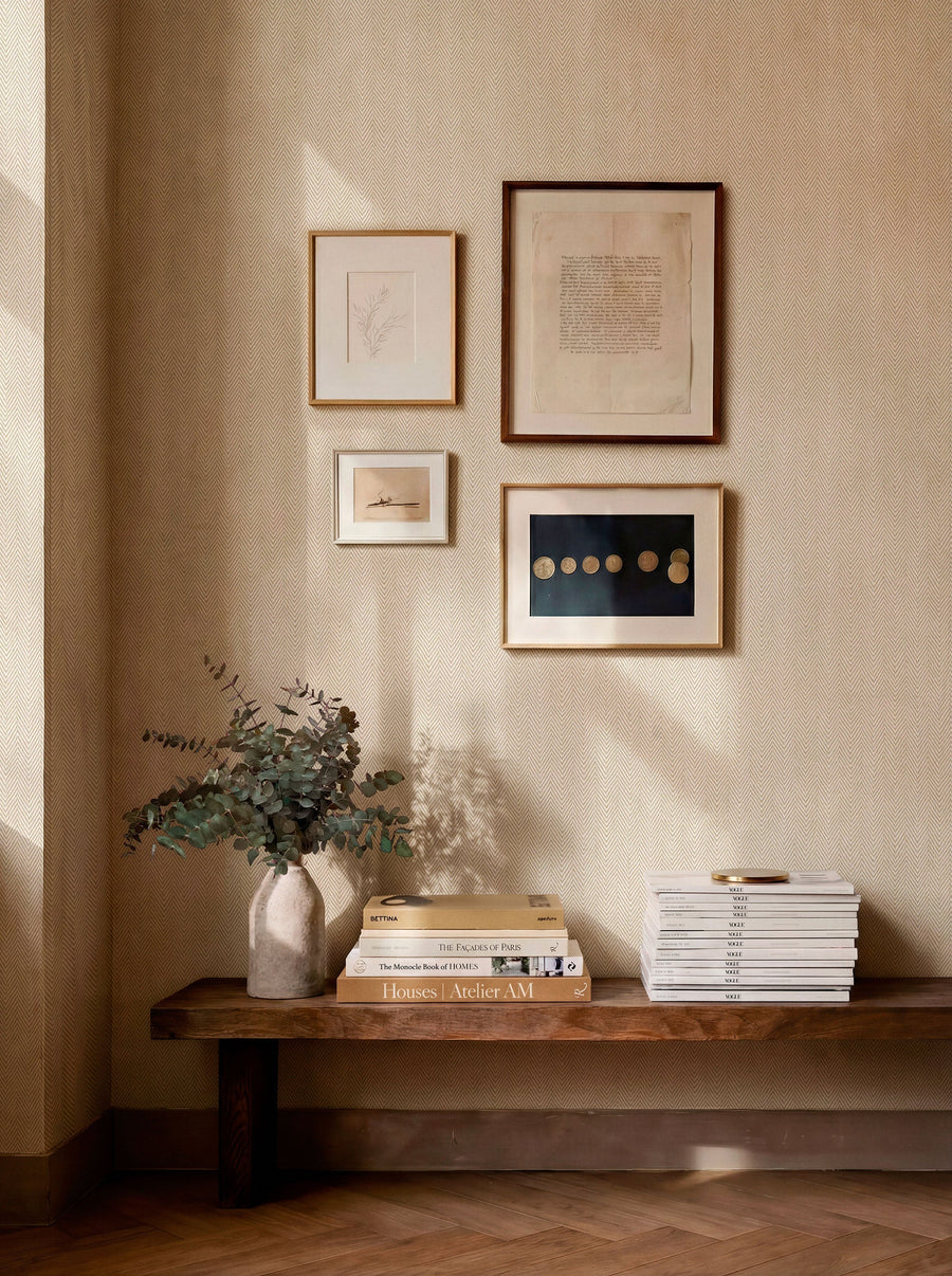 Espiguilla Beige and Nude wallpaper by Coordonne, a woven herringbone in warm neutral above a low bench and framed prints