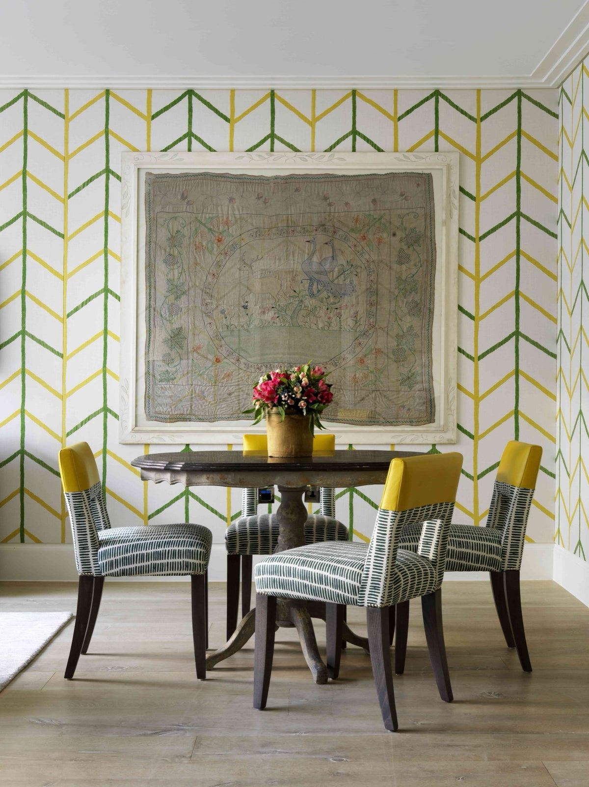 One Way by Kit Kemp, green and yellow chevrons on the wall of a dining corner with striped chairs